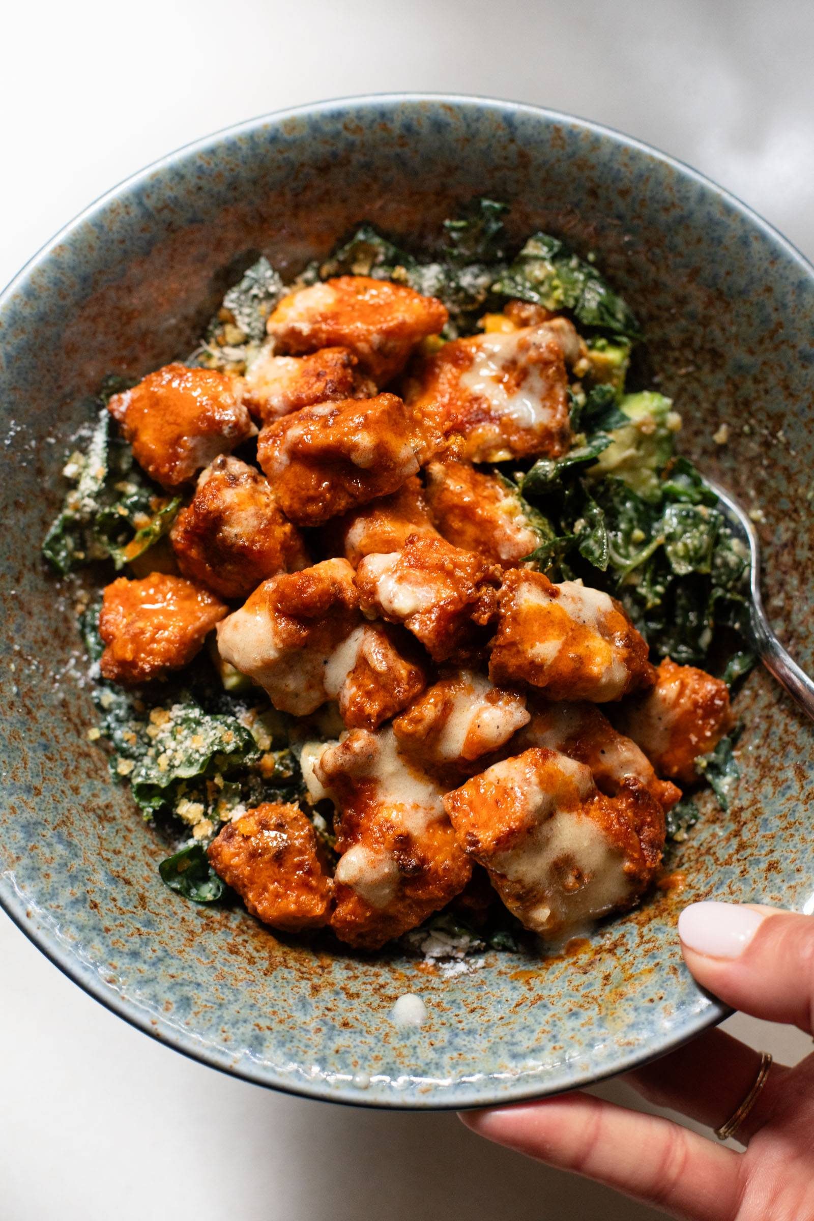 Crispy buffalo tofu on a kale caesar salad.
