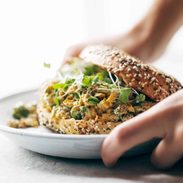 A person placing down a plate with a sandwich on it.