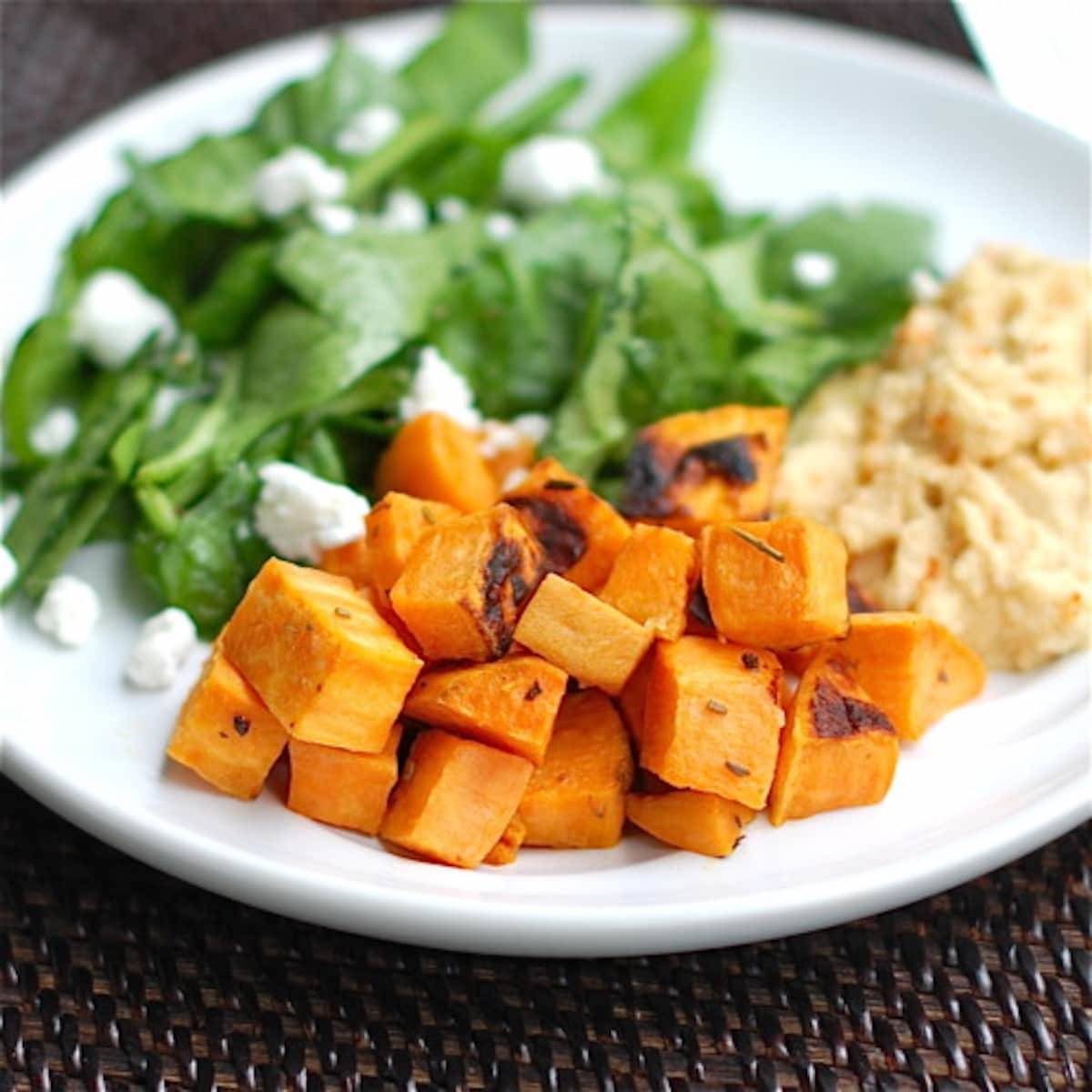 Roasted sweet potatoes with a side of hummus and a spinach salad.