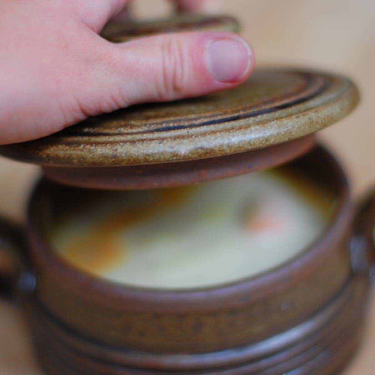 Root vegetable stew in a bowl with a lid.