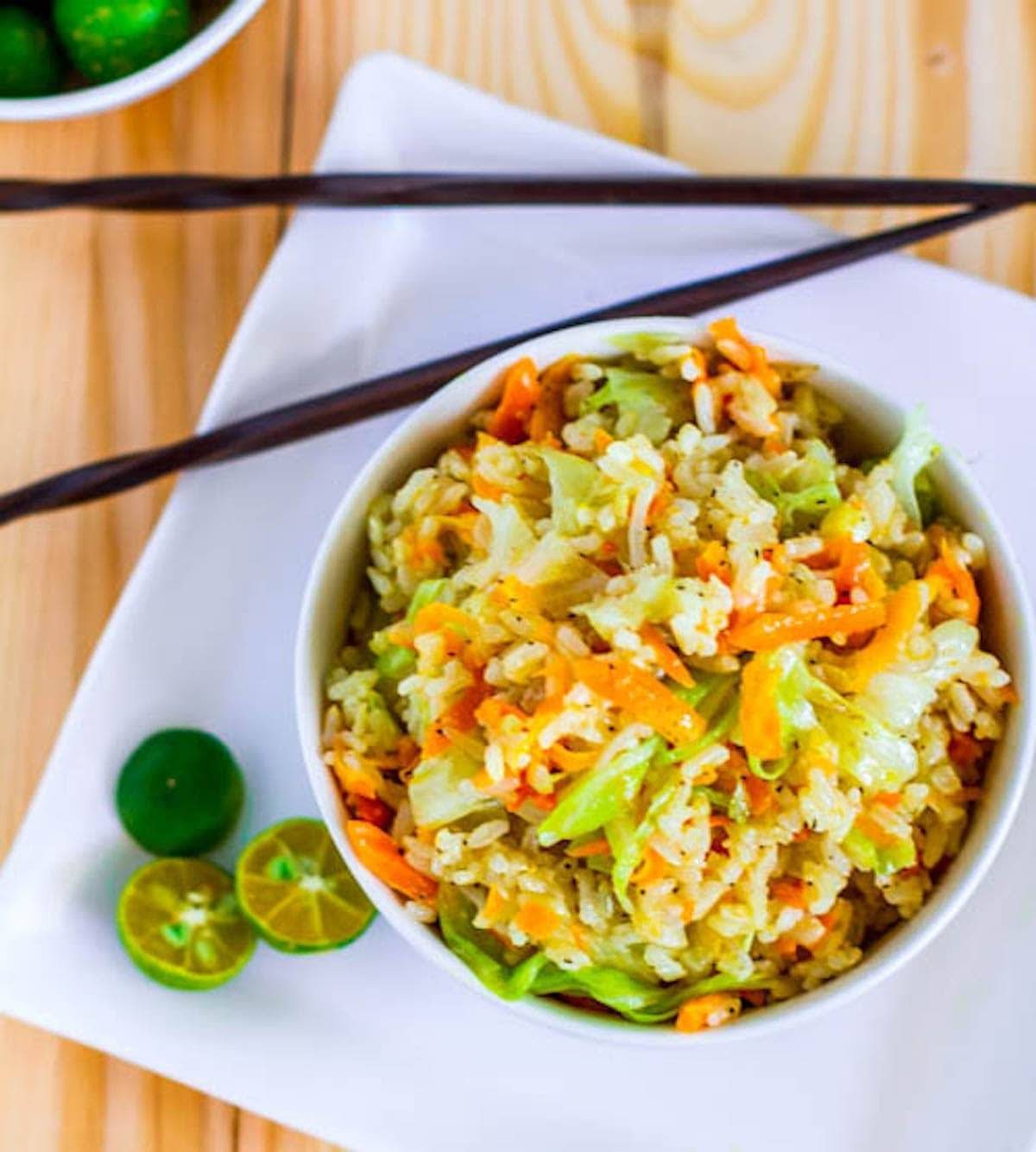 Skinny Garlic Fried Rice in a bowl with limes and chopsticks.