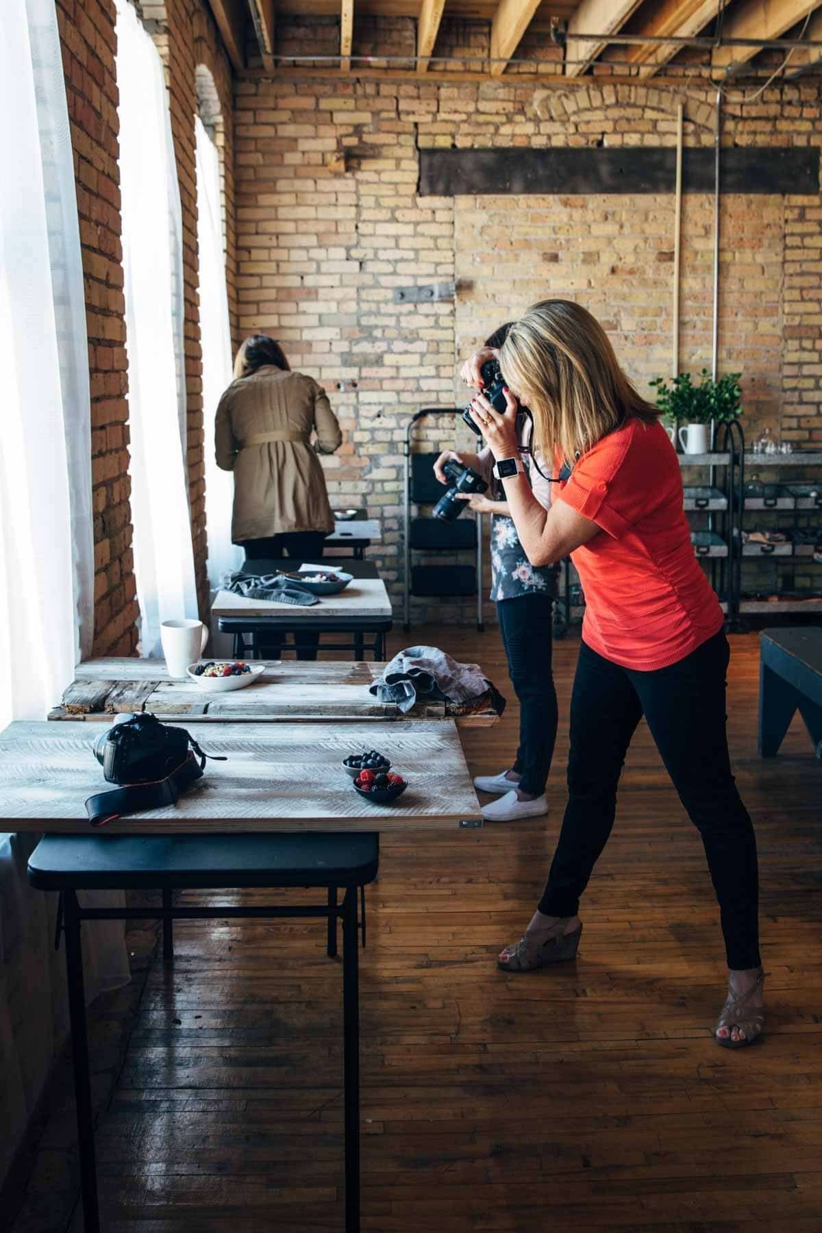 Woman with a camera taking a photo of food on a plate.