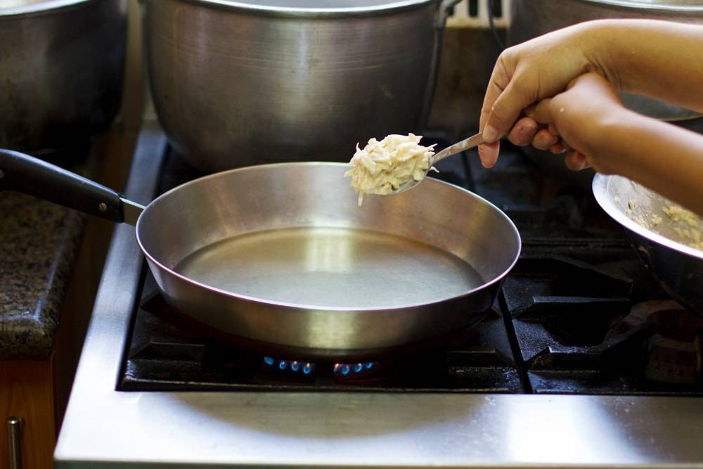 Camotes on a spoon over a pan.