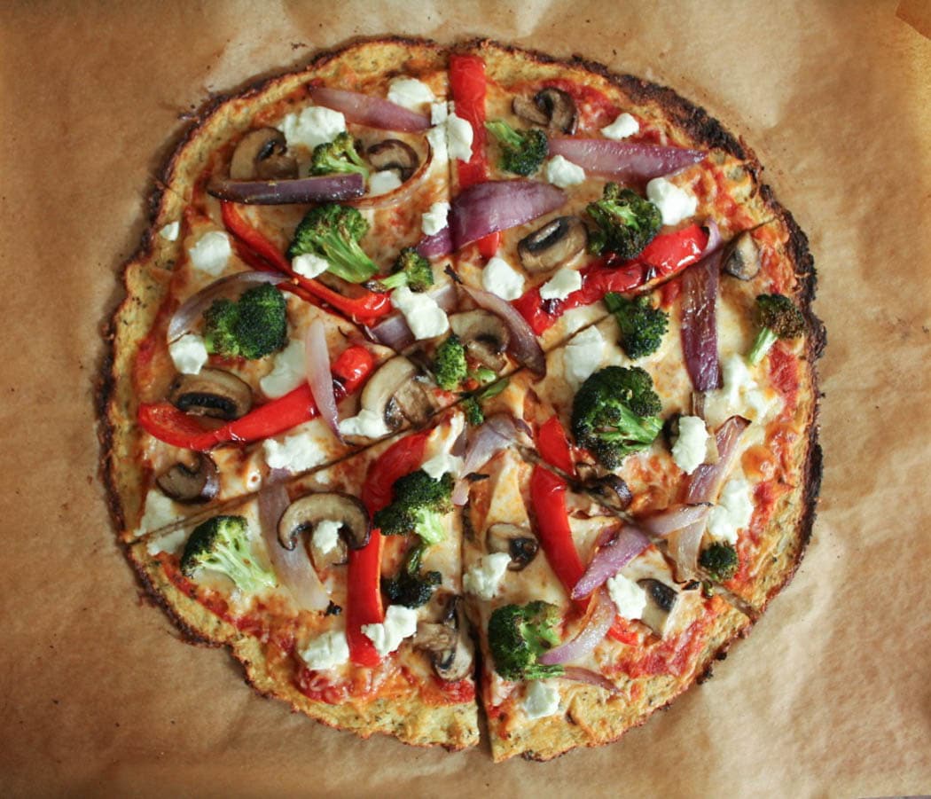 Sliced cauliflower pizza crust topped with roasted vegetables and goat cheese.