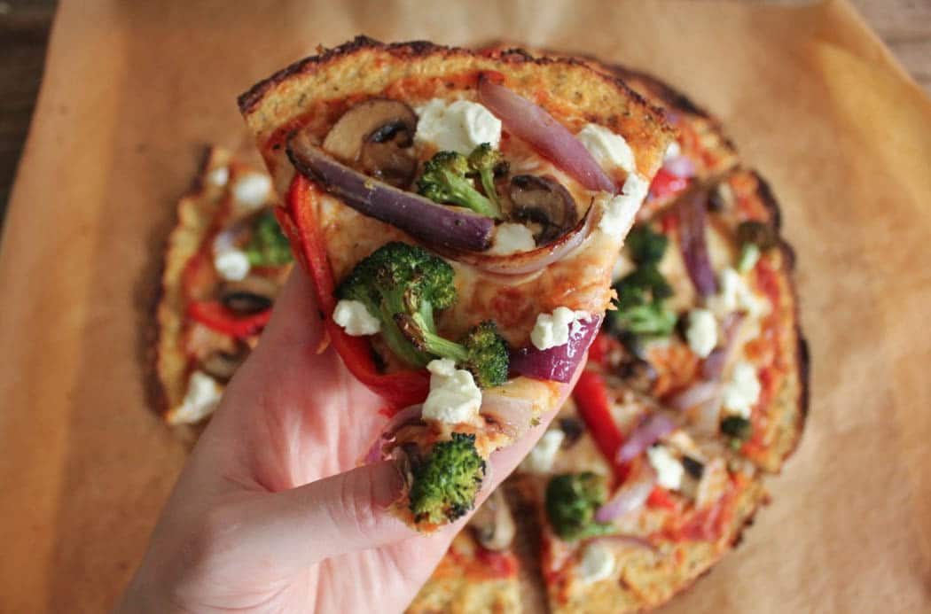 Slice of cauliflower crust pizza with roasted cauliflower and goat cheese.