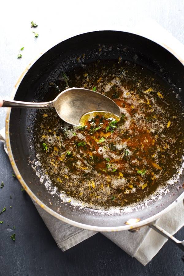 Brown butter in a pan with a spoon.