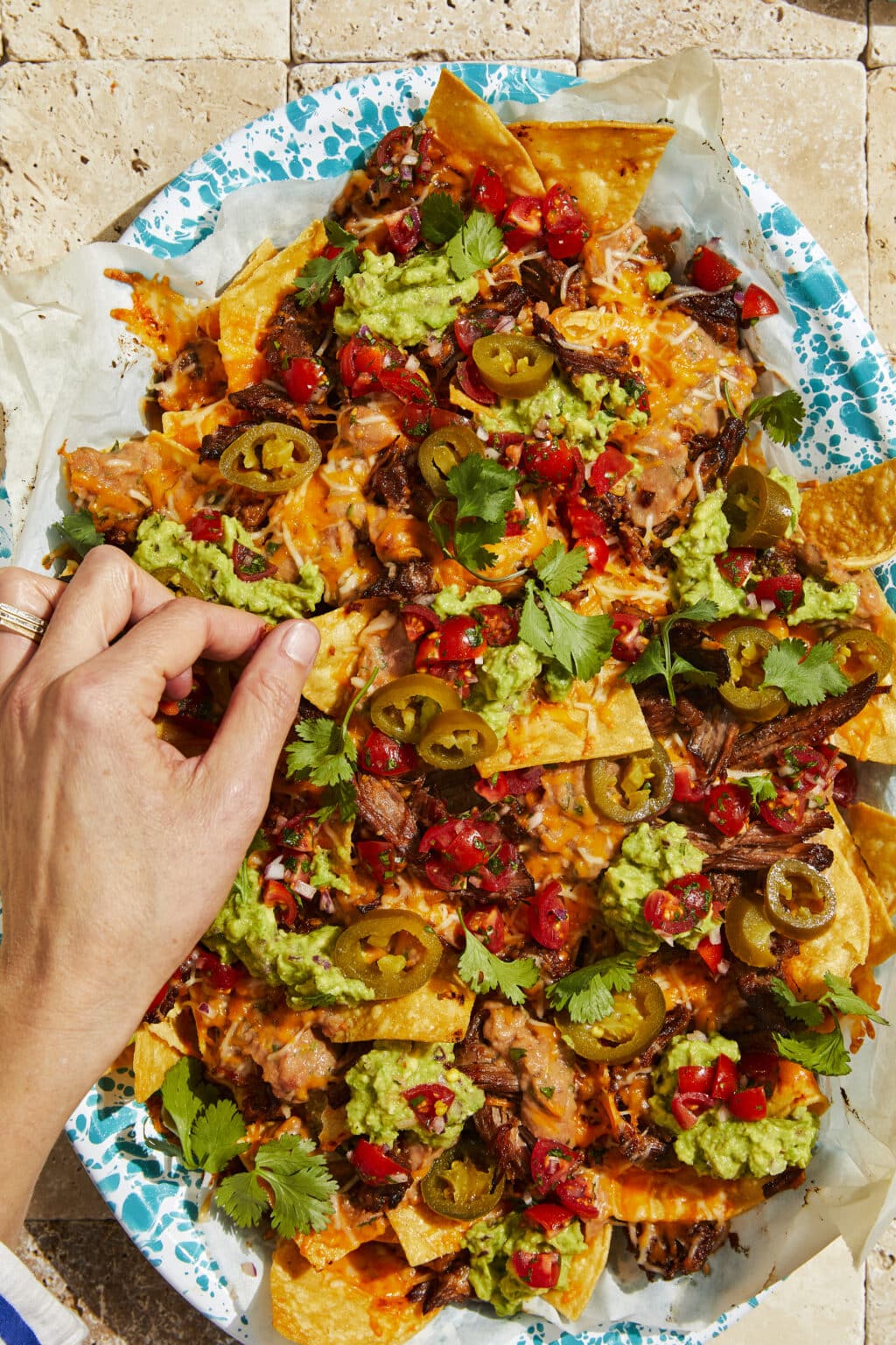 Overhead shot of nacho platter with braised bbq short ribs, guacamole, pico de gallo, and