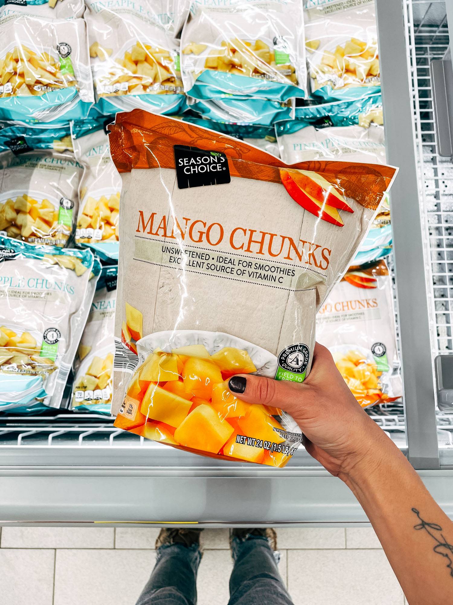 White hand holding a bag of frozen mango