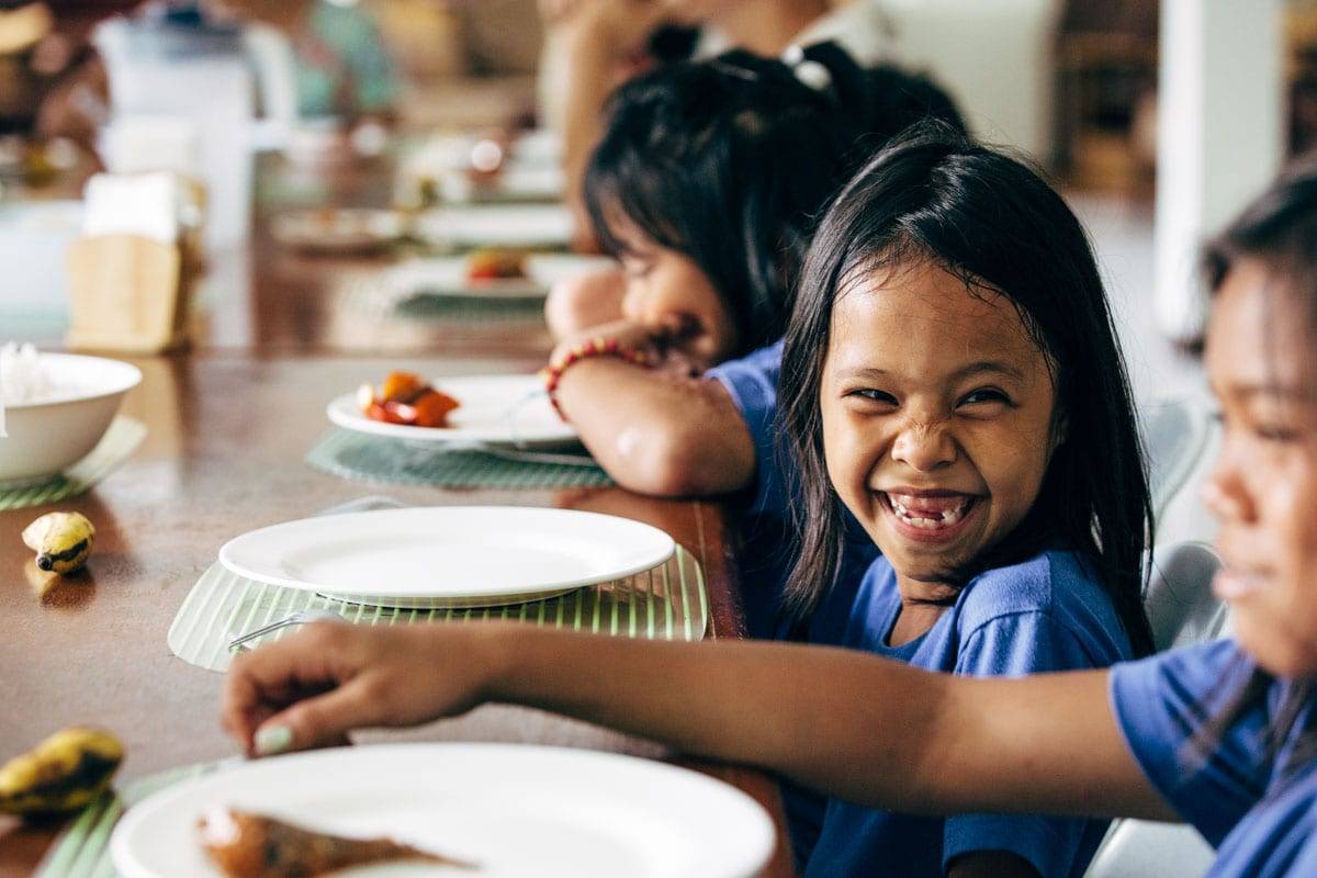 Little girl sitting at a table smiling.
