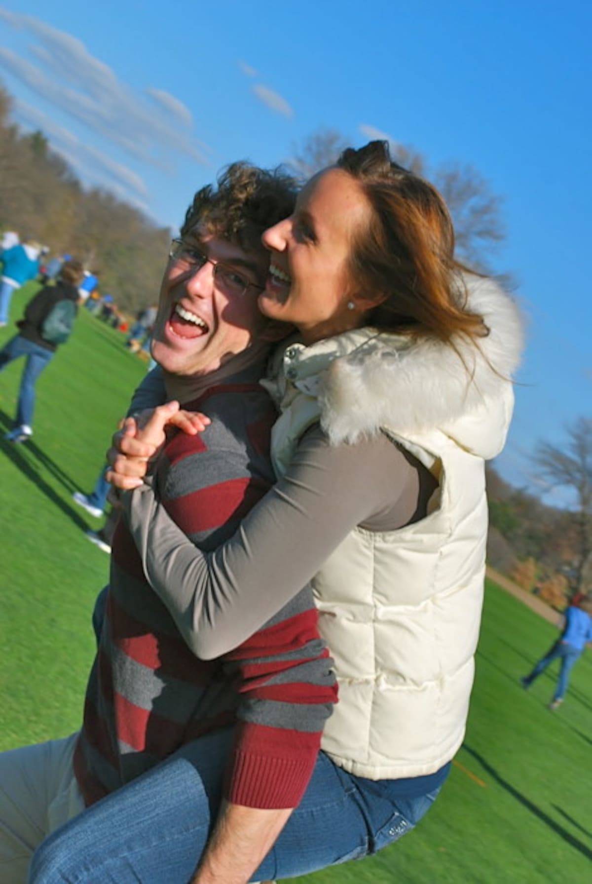Woman on a man's back running in a field.