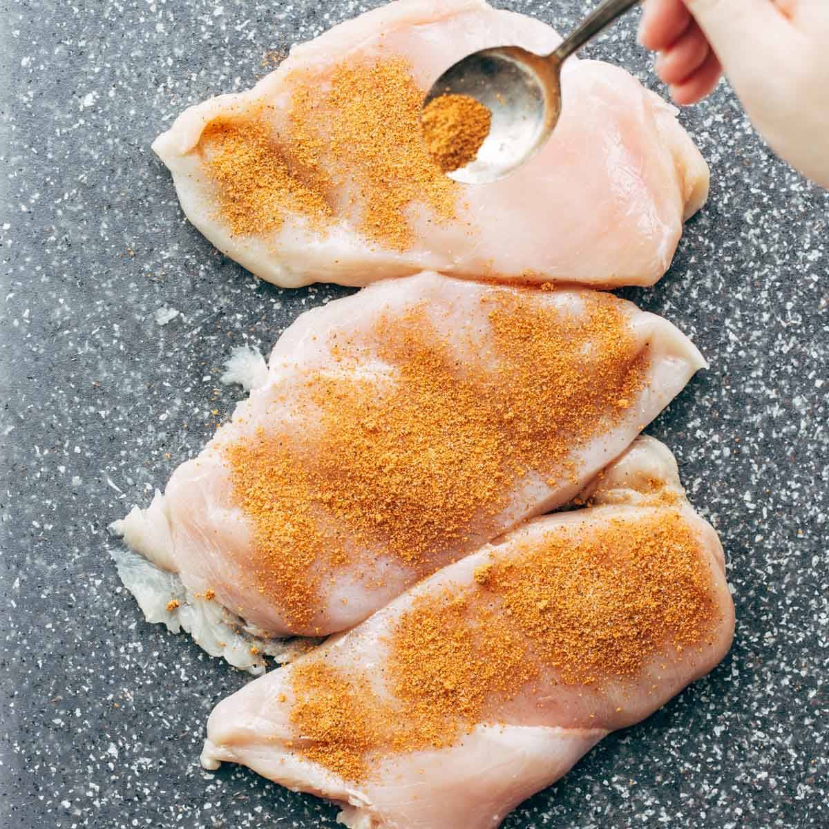 Seasoning chicken breasts.