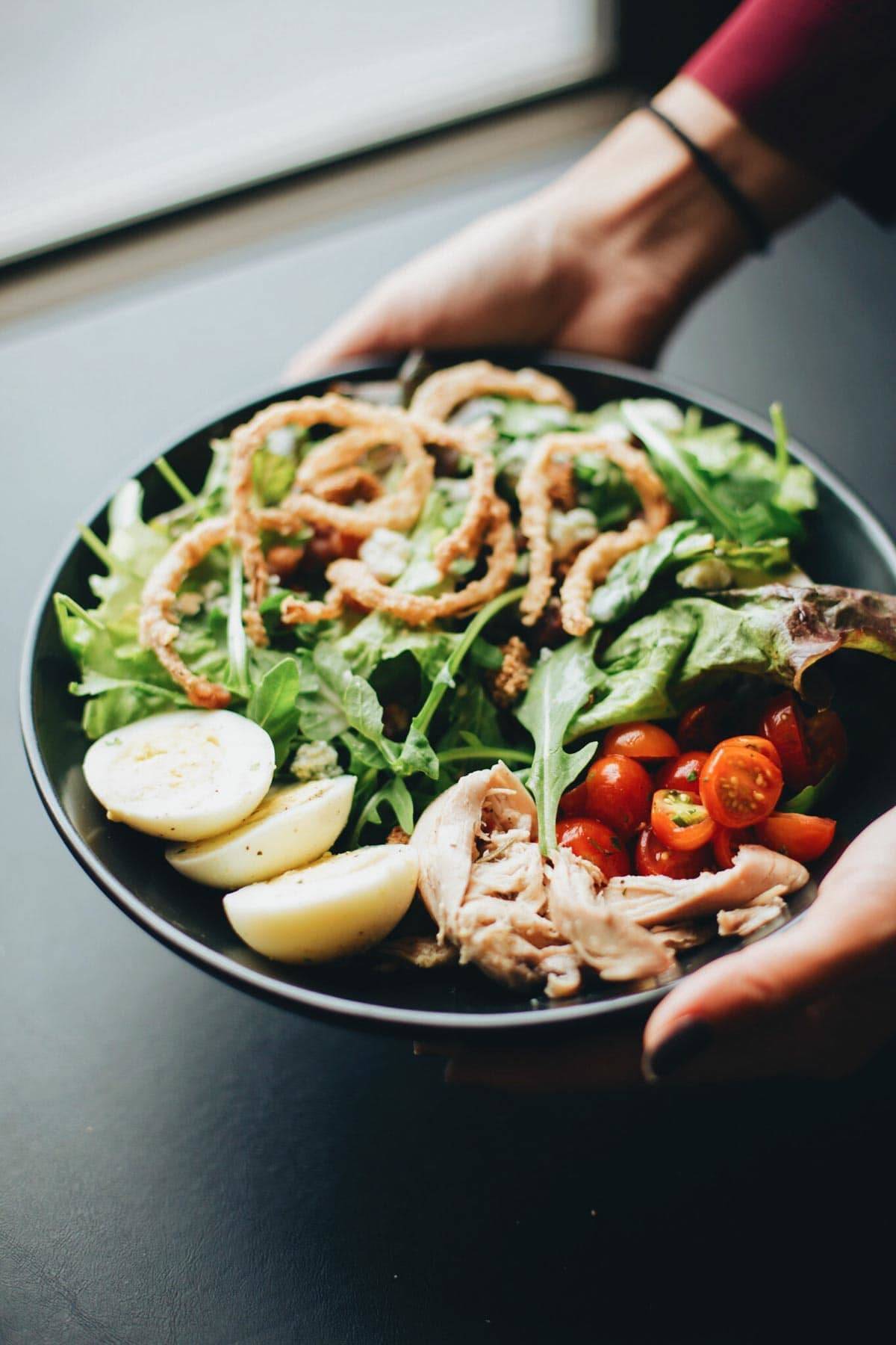 Hands holding a plate of food.